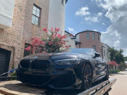 Black BMW on a flatbed beside a building