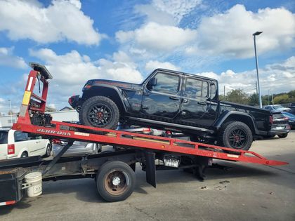 Black Jeep pickup loaded on a red flatbed